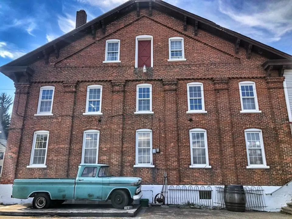 Old Mill’s three-story brick building with a vintage teal pickup truck parked out front
